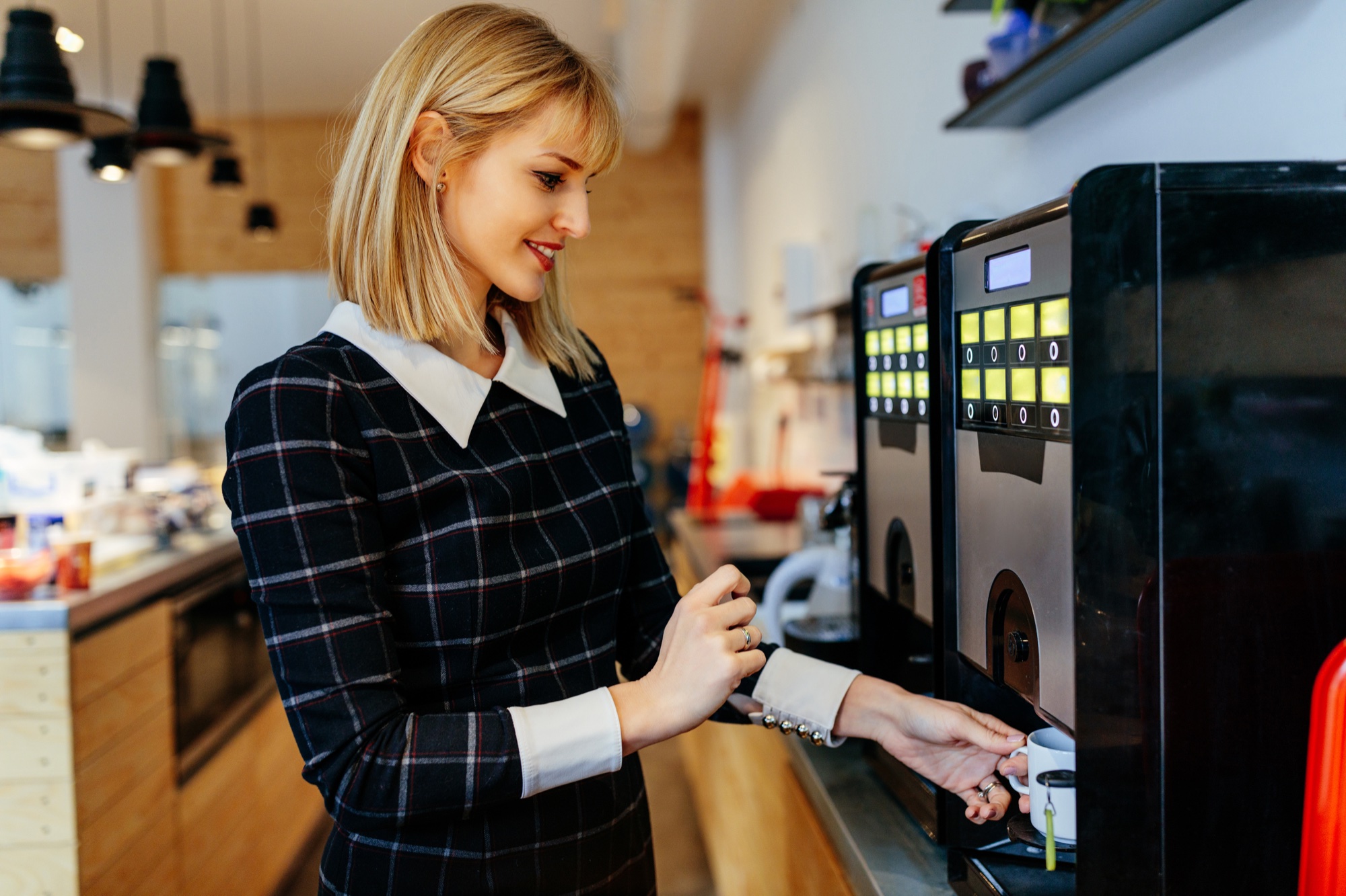 Customer drawing a fresh cup at a commercial café coffee machine