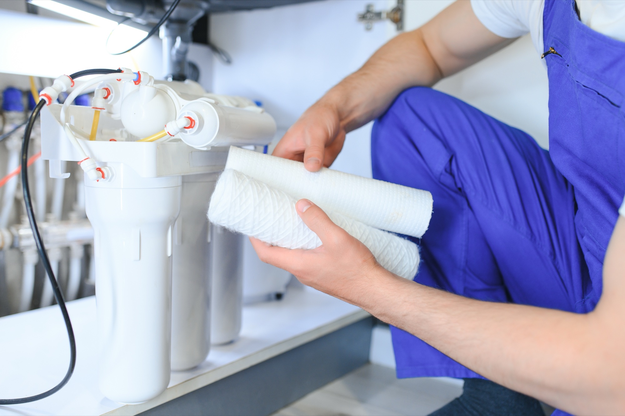 Plumbing technician replacing sediment cartridges on an under-sink filtration system
