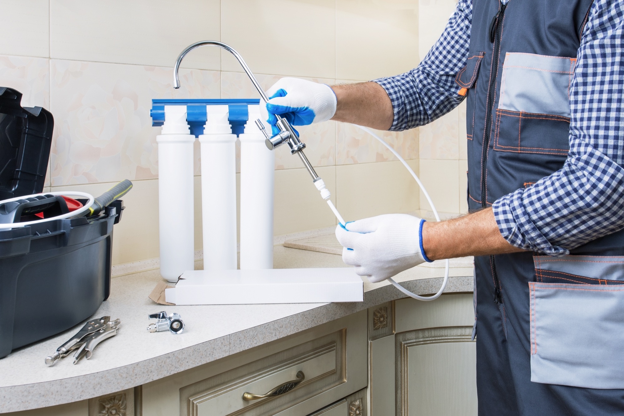 Technician connecting an under-counter filtration system on a kitchen countertop